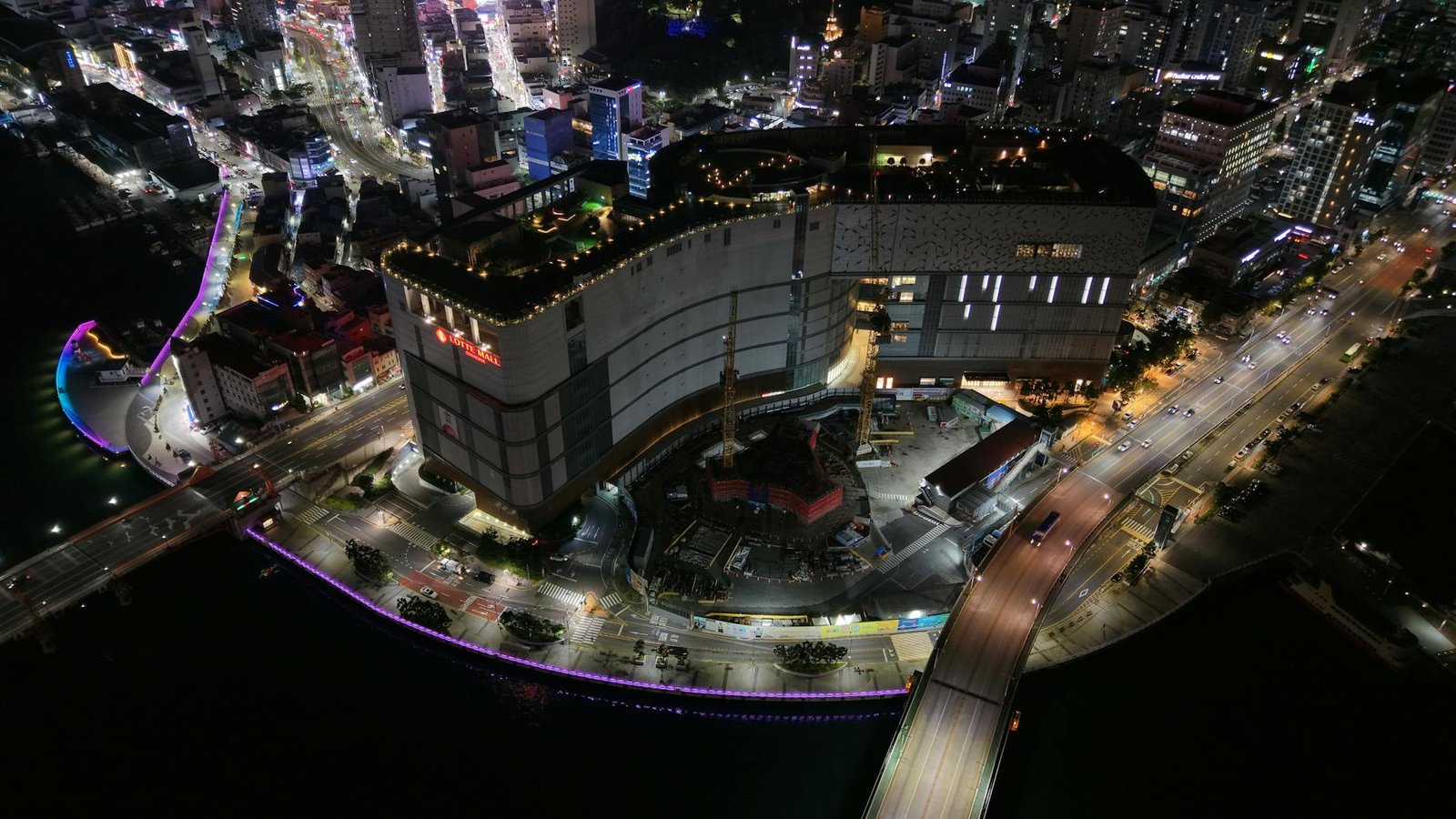 Aerial night view of Busan city showcasing vibrant lights and architecture.