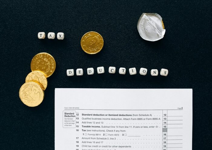 Image of tax deductions concept with coins and tax form on black background.