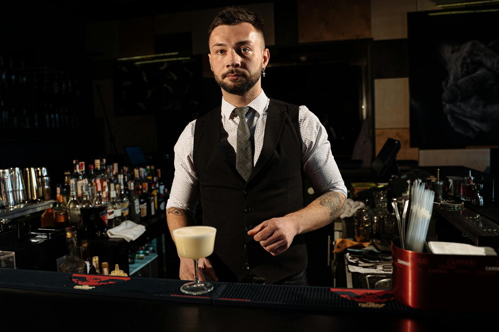 Professional bartender in a stylish lounge bar serving a creamy cocktail with confidence and charisma.