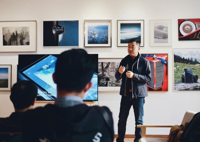 Man giving a presentation in a modern art gallery setting, engaging audience.