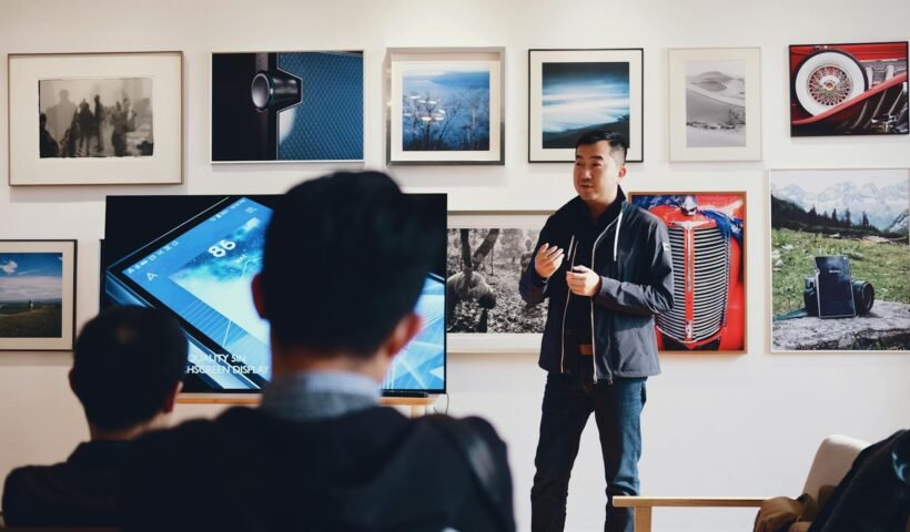 Man giving a presentation in a modern art gallery setting, engaging audience.
