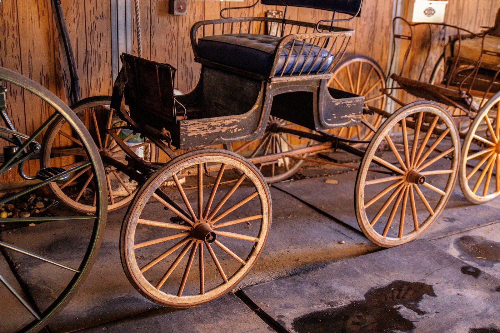 Close-up of an antique wooden carriage with vintage wheels in a barn setting.