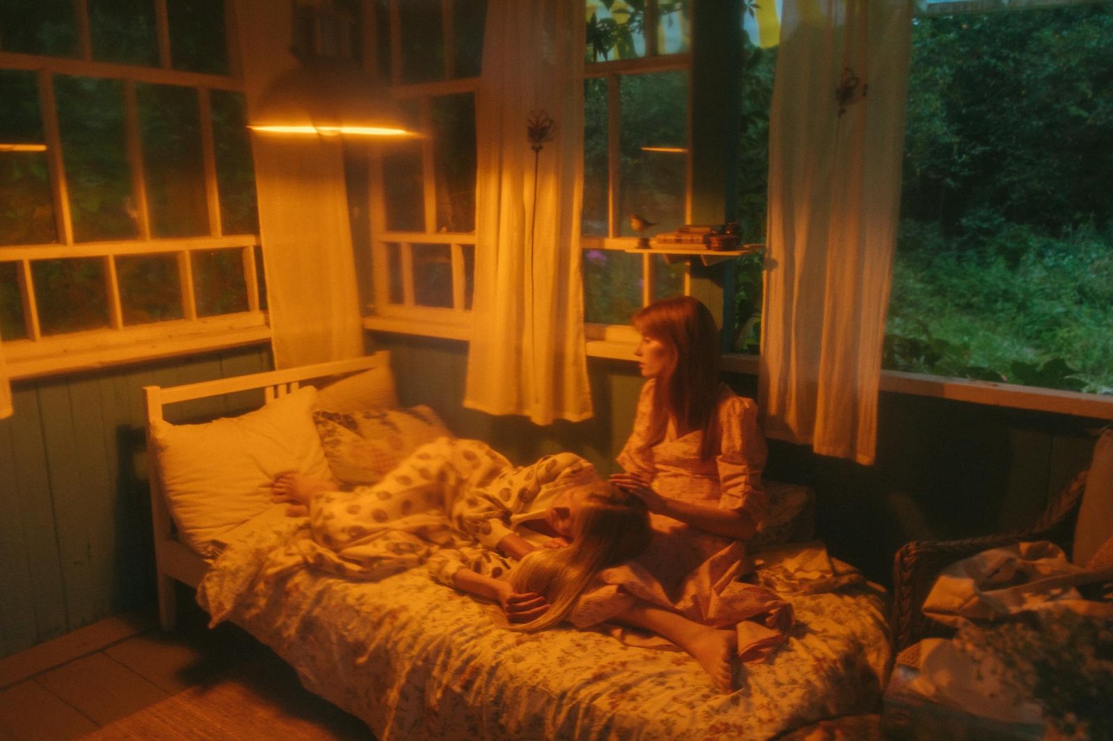 A serene moment of a woman and child in a warmly lit countryside bedroom.