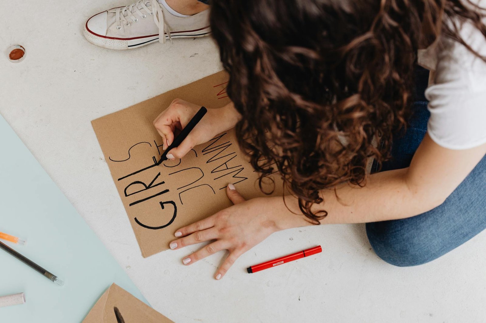 Young woman creates empowering protest sign at home, focusing on feminism and creativity.