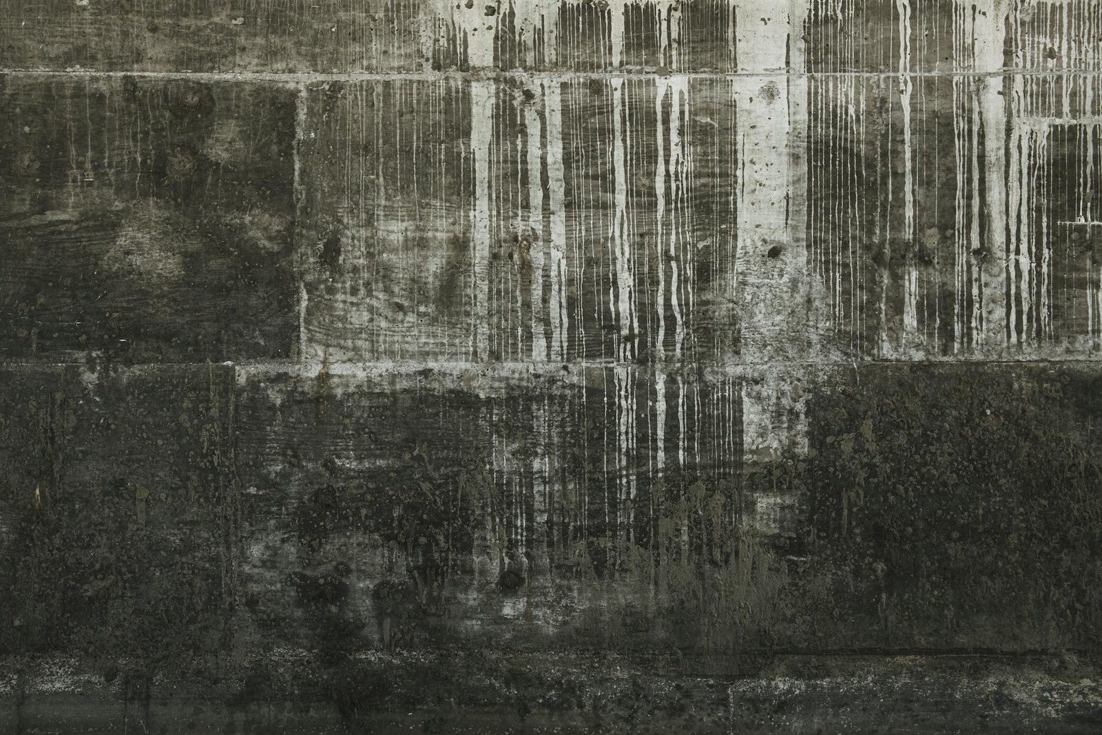 Detailed close-up of a weathered concrete wall showcasing texture, drips, and stains.