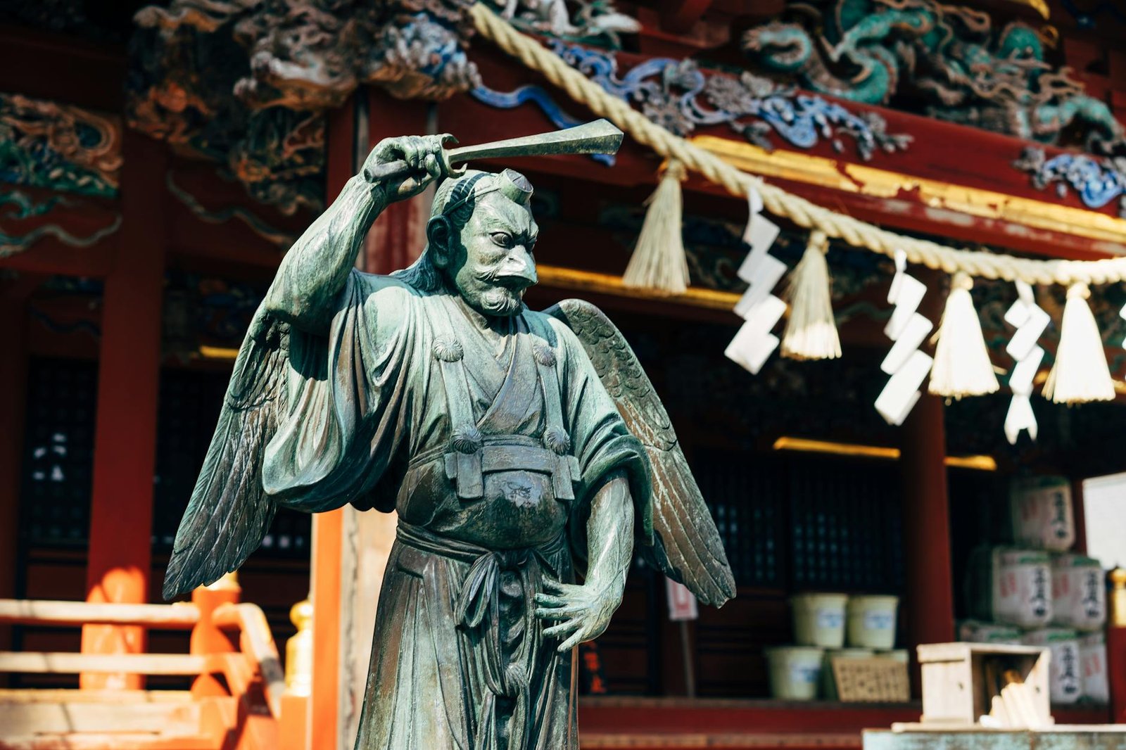 Bronze statue of a Japanese deity at a traditional shrine, showcasing intricate details.