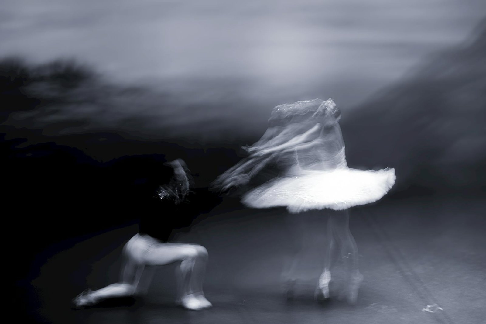 Artistic blur captures ballet dancers in dynamic motion, creating a dreamlike scene.