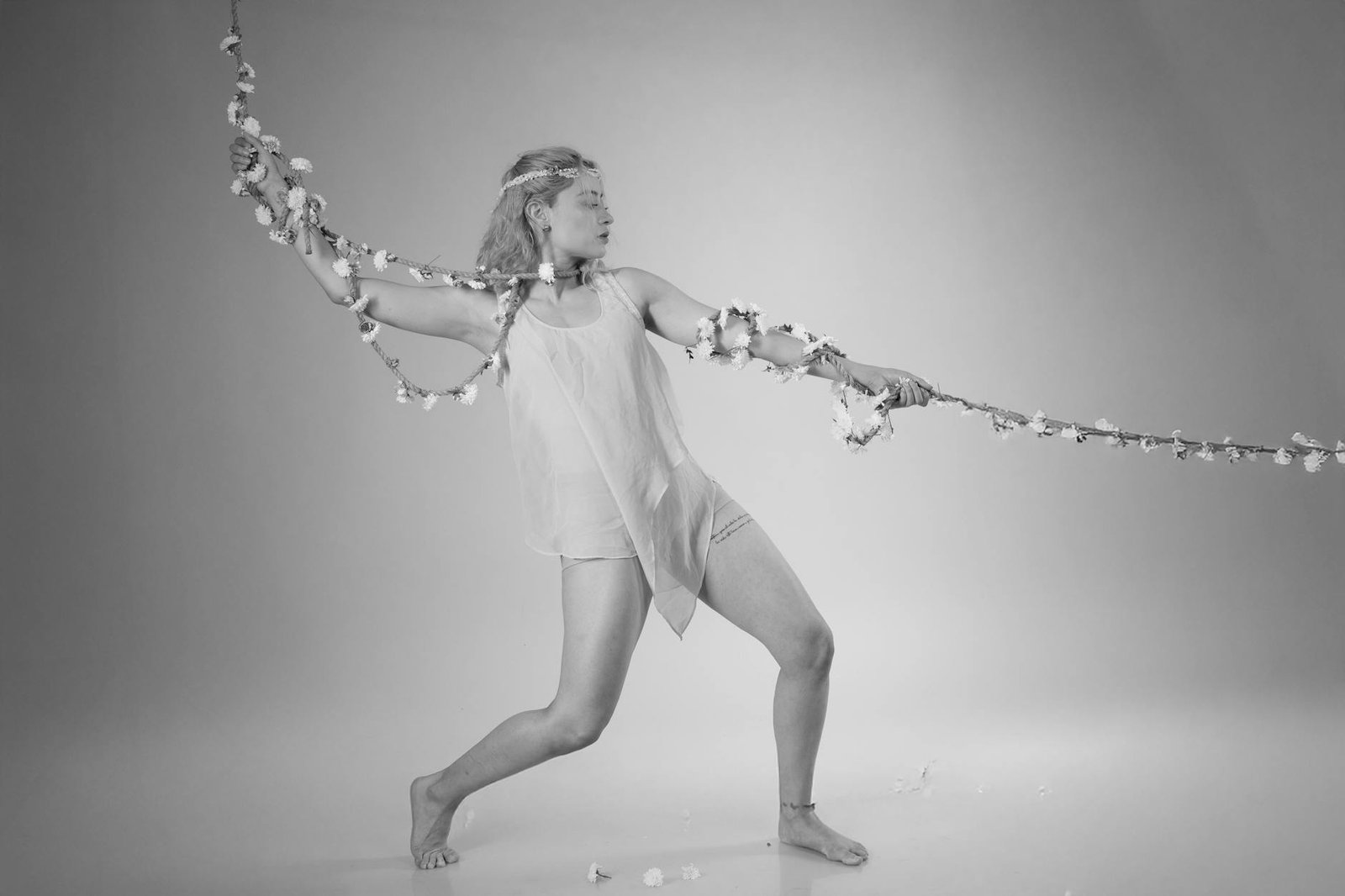 Graceful contemporary dancer posing with flower garland, showcasing elegance and movement.