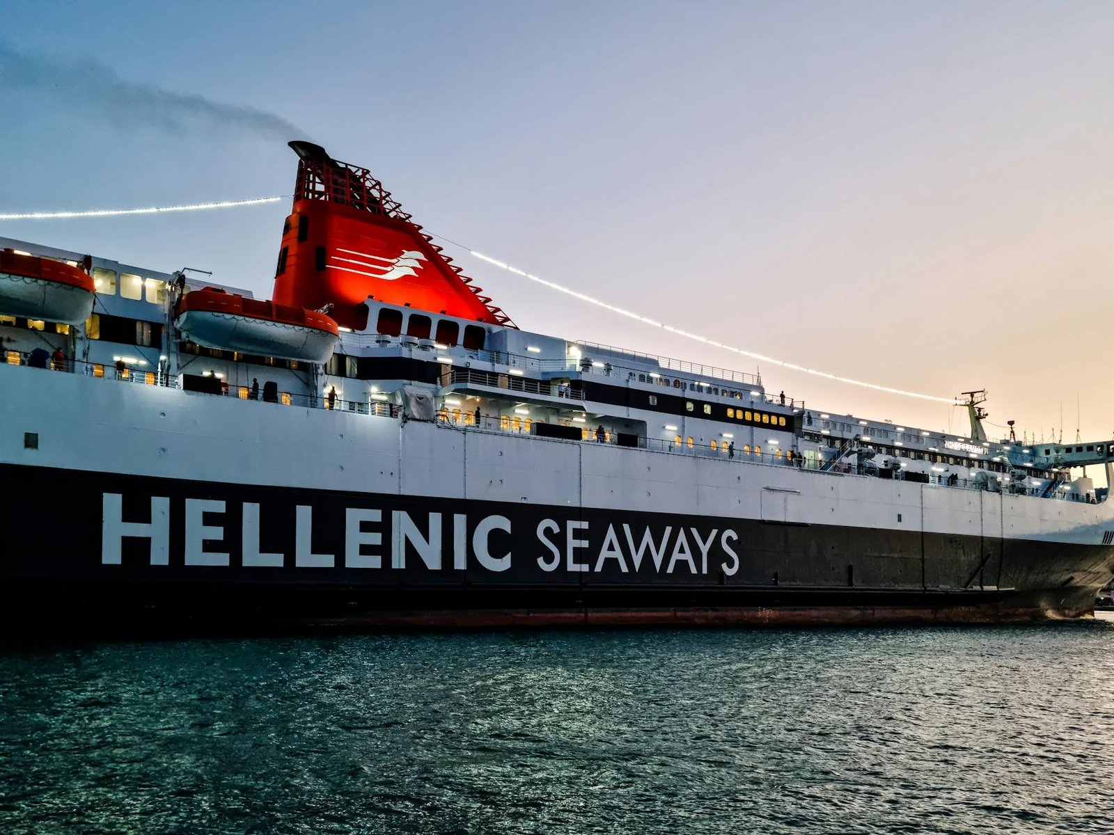 Hellenic Seaways ferry illuminated at sunset near Chios, Greece, showcasing maritime travel.