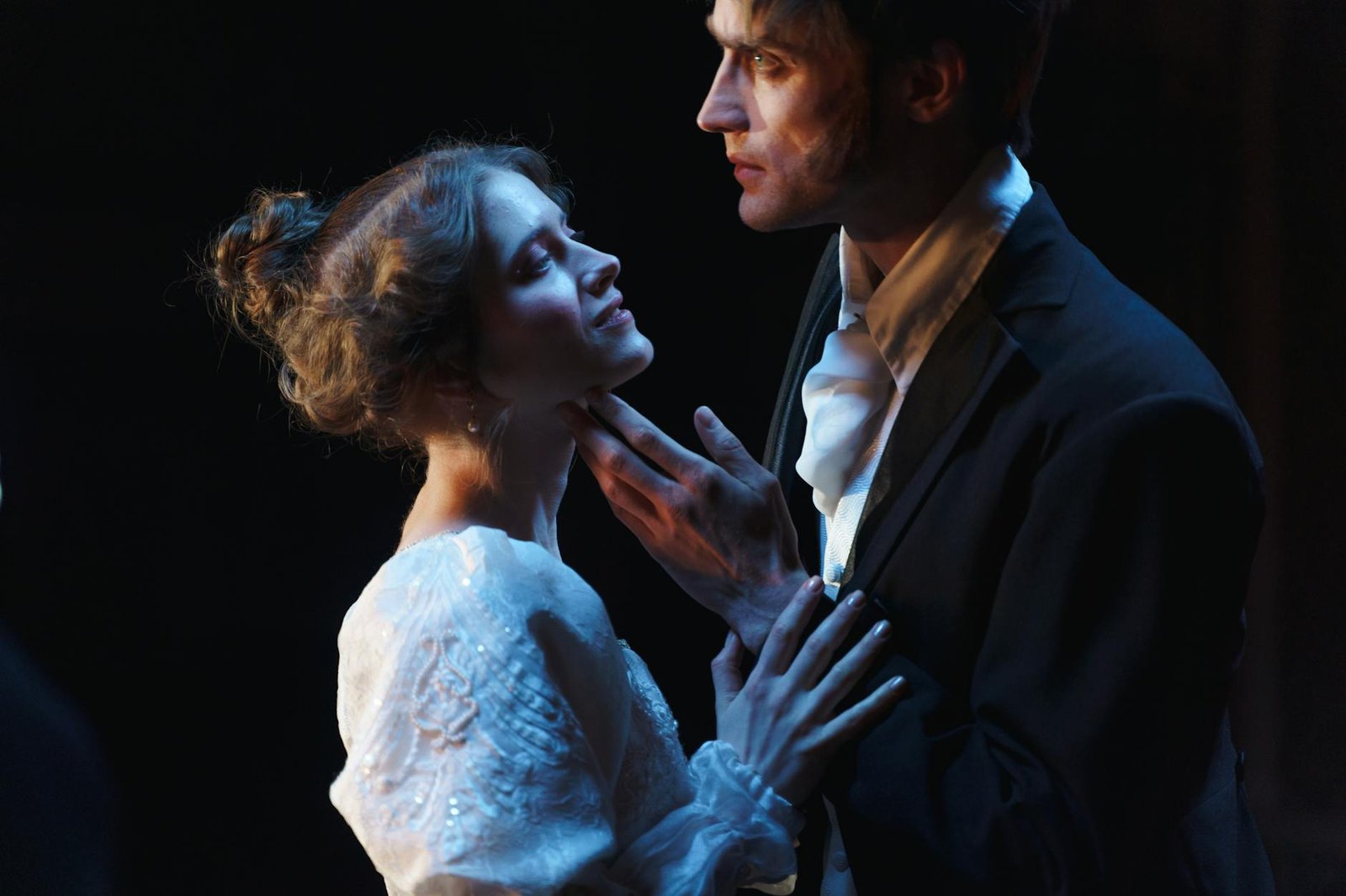 A romantic moment between a couple on stage, set against a theatrical backdrop.